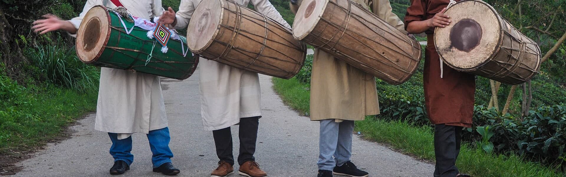 A close documentary view of four cylindrical Chyabrung drums suspended from their players’ shoulders.
